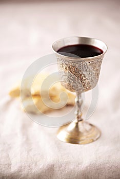 Unleavened bread, chalice of wine, silver kiddush wine cup on canva background. Communion still life. Christian communion concept