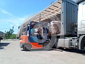 Unloading bags of cement from a truck with a forklift