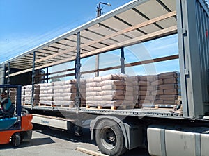 Unloading bags of cement from a truck with a forklift