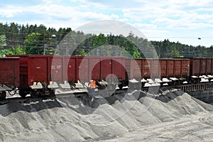 Unloading bulk cargo from railway wagons on of high railway platform.