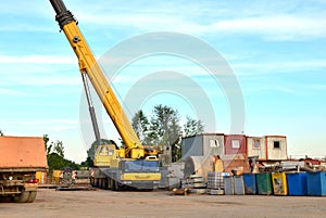Unloading of cargo and building materials by mobile truck crane at the construction site.