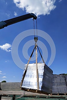 Unloading the front brick using a mobile crane in the village in private territory.