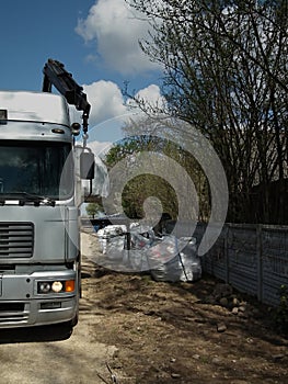 Unloading large transport sacks containing granite cobblestones.