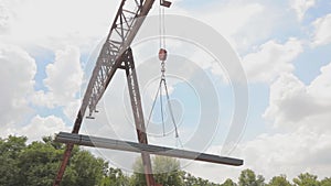Unloading of the profile pipe by a gantry crane from a freight car, loads metal in a warehouse, a large gantry crane