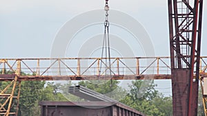 Unloading of the profile pipe by a gantry crane from a freight car, loads metal in a warehouse, a large gantry crane