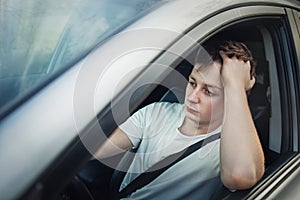 Unlucky and fatigue driver stuck in a traffic jam, looking upset out of his car window