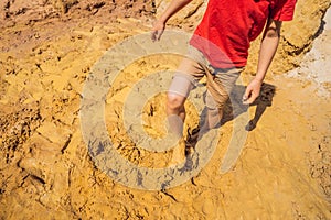 Unlucky person standing in natural quicksand river, clay sediments, sinking, drowning quick sand, stuck in the soil