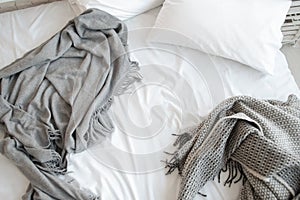 Unmade bed with pillow and gray blankets top view