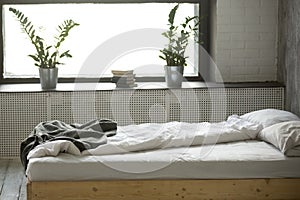 Unmade messy bed in modern bedroom interior with nobody