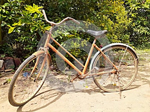 A unmaintained old orange bicycle