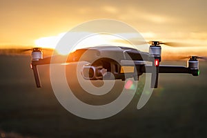 Unmanned quadcopter in flight with a digital camera at sunset. Drone silhouette at sunset