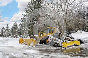 Unmarked snow plow vehicles sit empty in a parking lot after a winter storm in the mountains of North Idaho, USA