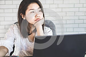 Unmotivated Asian female worker sitting at desk bored to work photo