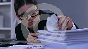 Unmotivated stressed office worker looking through papers, work overload closeup