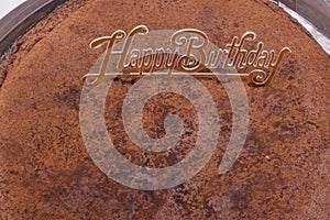 An unneat chocolate cake with happy bithday sign