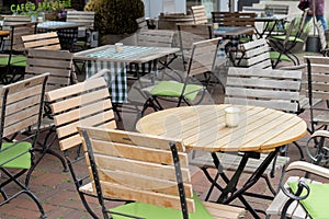 Unoccupied chairs and tables in a garden restaurant with table legs and chair legs made of iron and wooden tops