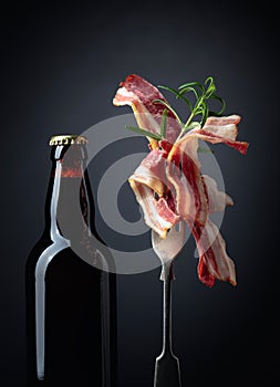 Unopened beer bottle and slices of fried bacon