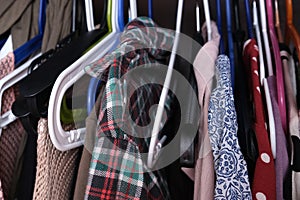 Unorganized clothes of different colors hanging in a wardrobe in mess close up, storage and order at home, cleaning and