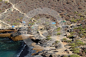 Punta de Las Gaviotas wild camping. Unorganized tramper tourists settled on the arid rocky shores of Costa Adeje, Tenerife, Spain photo