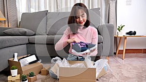 Unpack package and open parcel when online shopping and good delivery. Asian woman lifestyle in living room at home.