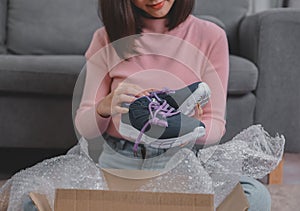 Unpack package and open parcel when online shopping and good delivery. Asian woman lifestyle in living room at home.