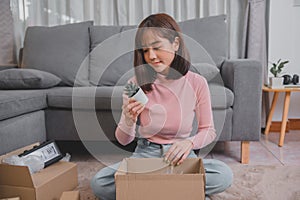 Unpack package and open parcel when online shopping and good delivery. Asian woman lifestyle in living room at home.