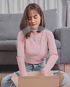 Unpack package and open parcel when online shopping and good delivery. Asian woman lifestyle in living room at home.