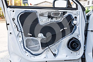 Unpack white steel vehicle door panel with replaced with new speaker in auto accessories shop