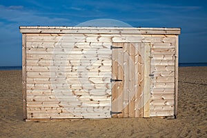 Unpainted beach hut. New wooden shed on the sand.