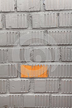 Unpainted brick of wall, one orange rectangle between grey blocks, background