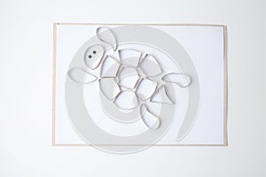 Unpainted turtle craft made from cardboard pieces on white paper. DIY children art project with empty cutout shapes photo