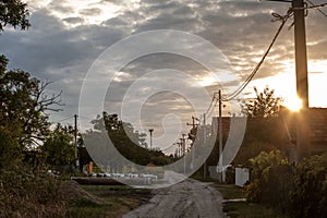 Unpaved non asphalted road and street, a dirtpath, in a village at sunset in Ovca, a rural settlement near Belgrade, Serbia