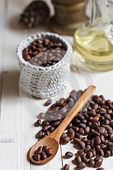 Unpeeled pine nuts in bulk on a table with a wooden spoon close-up