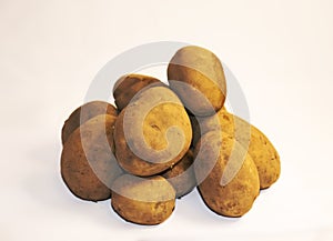 Unpeeled potatoes on a white background, several pieces of vegetables