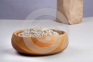 Unpeeled raw oats in a wooden plate on a Gray background