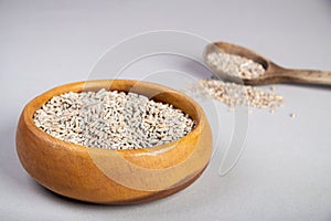 Unpeeled raw oats in a wooden plate on a Gray background