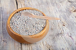 Unpeeled raw oats in a wooden plate on a wooden table