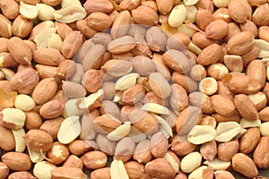 Unpeeled, raw peanuts are scattered on the table and make up the background of healthy plant products, the legume family