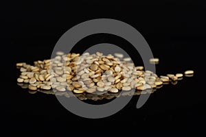 Unpeeled sesame seeds isolated on black glass photo