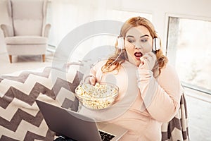 Unpleasant plus-size woman watching movie on her laptop