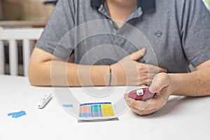 Unpleasantly surprised man looks at the results of blood sugar level measurement