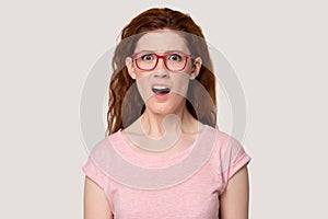 Unpleasantly surprised red-haired woman looking at camera head shot portrait.