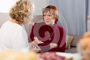 Unpleasantly surprised senior woman with female friend