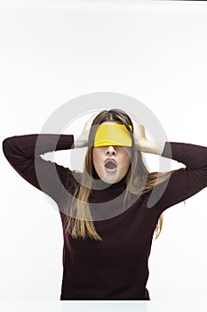 Unpleased Exclaiming Caucasian Woman in Burgundy Turtleneck Sweater With Yellow Sticky Note on Her Forehead. Against White