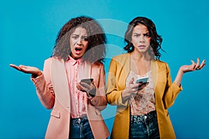 Unpleased girls using mobile internet. Studio shot of attractive african woman with phone in hand