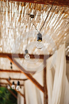 Unpluged garland of incandescent bulbs under the thatched ceiling. photo