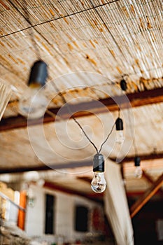 Unpluged garland of incandescent bulbs under the thatched ceiling. photo