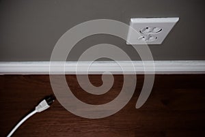 Unplugged cord on floor beside electrical outlet