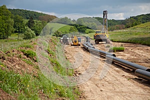 Unplugged gas pipeline in the coutryside diagonally from the right diagonally by photo with gas laying machines in the background