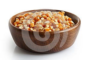Unpopped popcorn in dark wooden bowl.